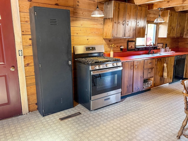 kitchen featuring sink, hanging light fixtures, wooden walls, and gas stove