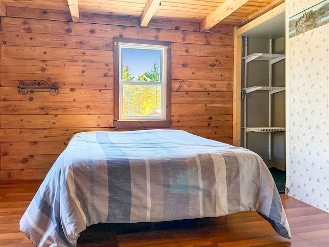 bedroom with beamed ceiling, wood walls, hardwood / wood-style flooring, and wood ceiling