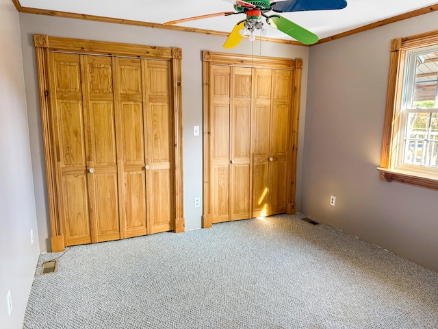 unfurnished bedroom featuring ceiling fan, ornamental molding, and carpet