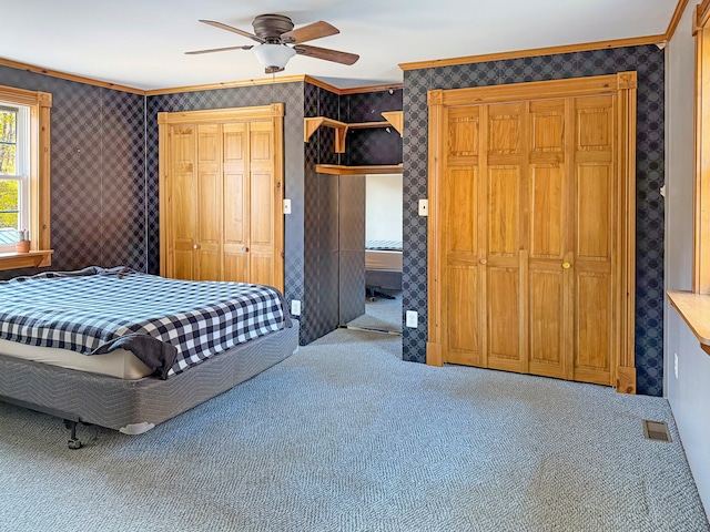 unfurnished bedroom featuring carpet flooring, ornamental molding, and ceiling fan