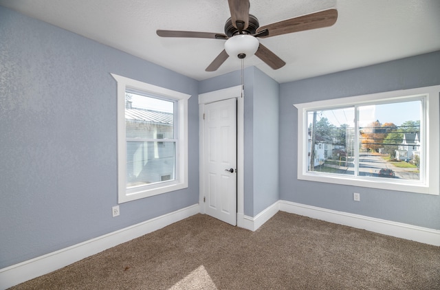 unfurnished bedroom featuring carpet flooring, multiple windows, a closet, and ceiling fan