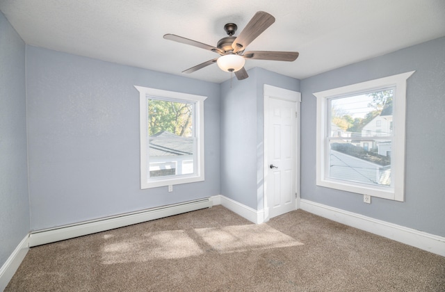 carpeted spare room with ceiling fan, a baseboard heating unit, and plenty of natural light