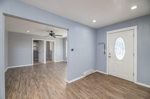 foyer entrance featuring a baseboard heating unit, hardwood / wood-style floors, and ceiling fan