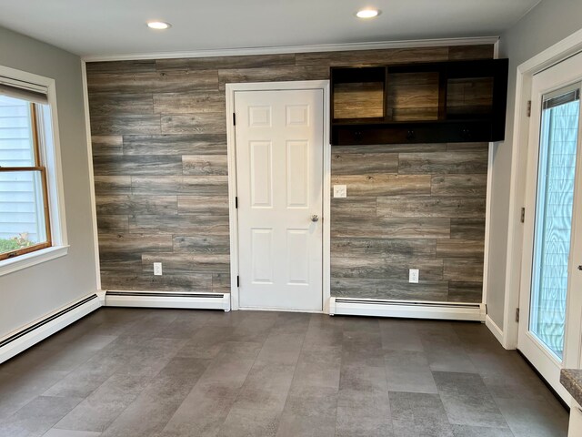 spare room with a wealth of natural light, a baseboard radiator, and wooden walls