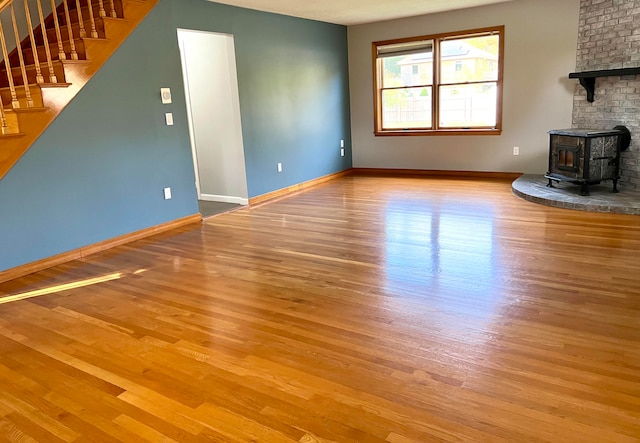 unfurnished living room featuring a wood stove and light wood-type flooring