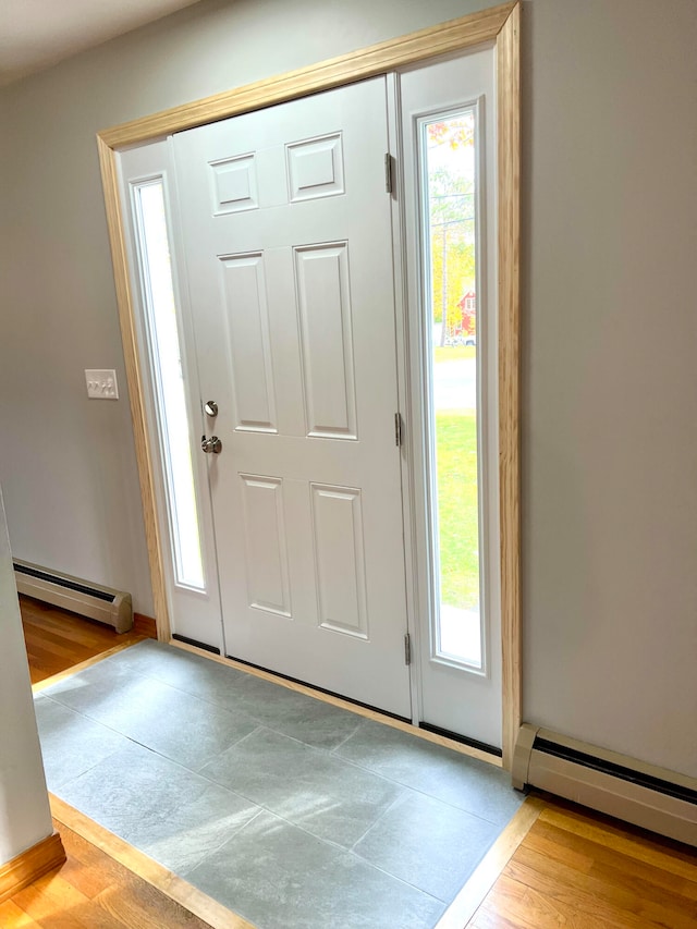 foyer entrance with light hardwood / wood-style flooring and a baseboard heating unit