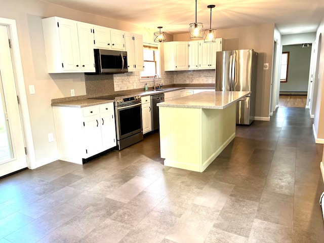 kitchen featuring tasteful backsplash, a center island, white cabinetry, stainless steel appliances, and decorative light fixtures