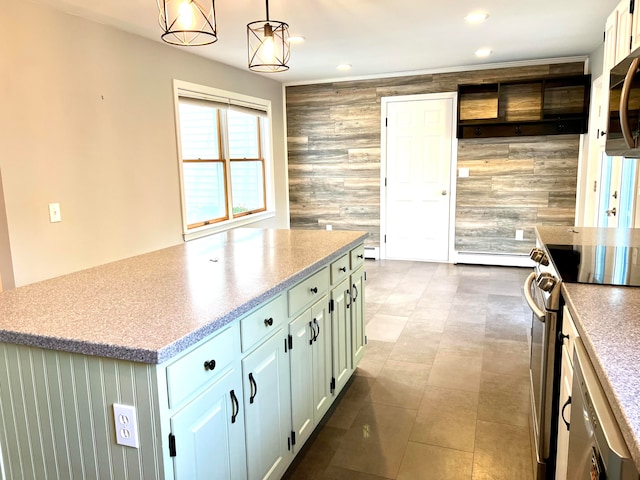 kitchen featuring wood walls, appliances with stainless steel finishes, a center island, white cabinetry, and decorative light fixtures