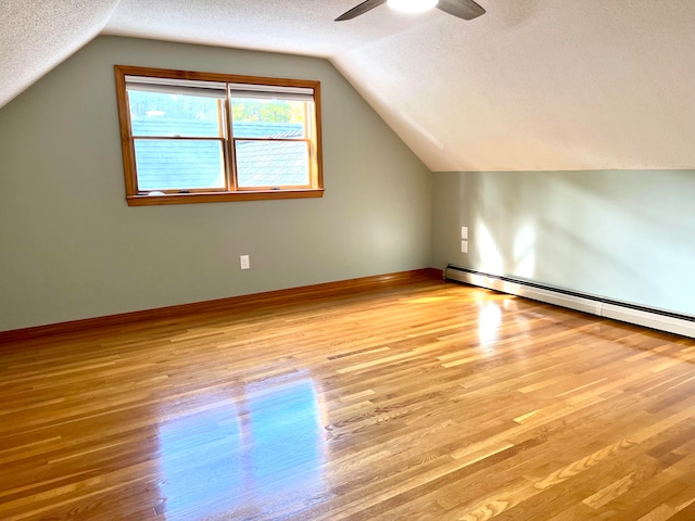 bonus room with a textured ceiling, light wood-type flooring, and vaulted ceiling