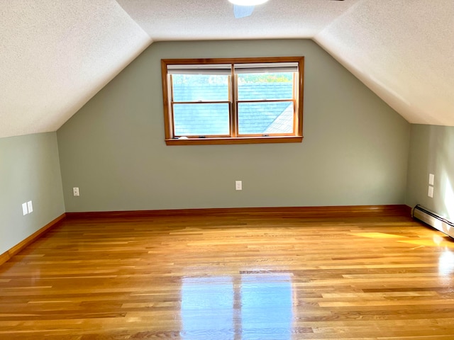 bonus room featuring light hardwood / wood-style flooring, a textured ceiling, and lofted ceiling