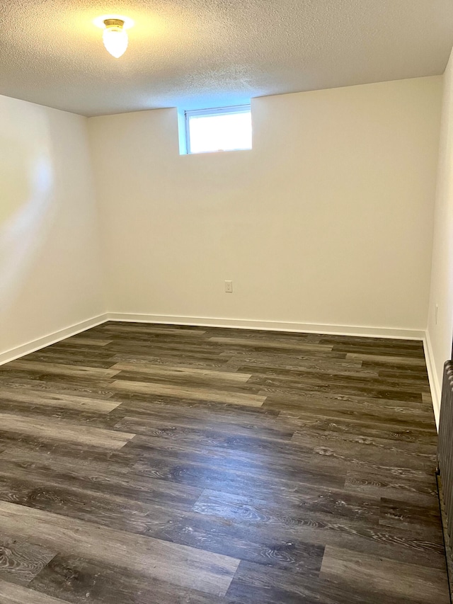 basement with a textured ceiling and dark hardwood / wood-style floors