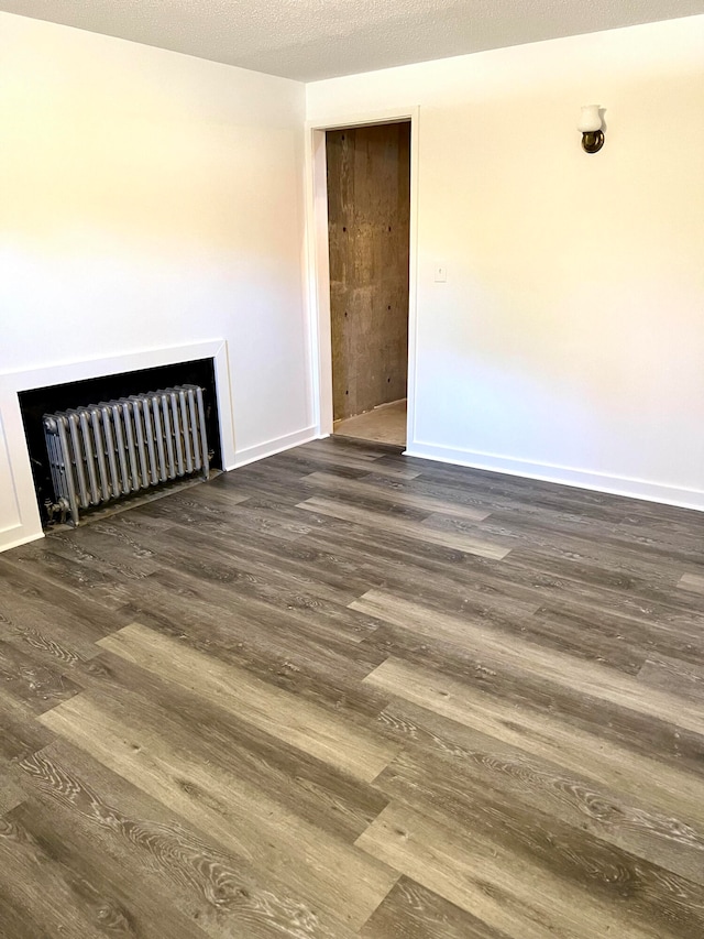 empty room featuring radiator, a textured ceiling, and dark hardwood / wood-style floors