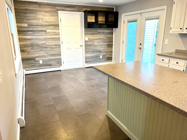 kitchen with a baseboard heating unit, white cabinetry, and wood walls