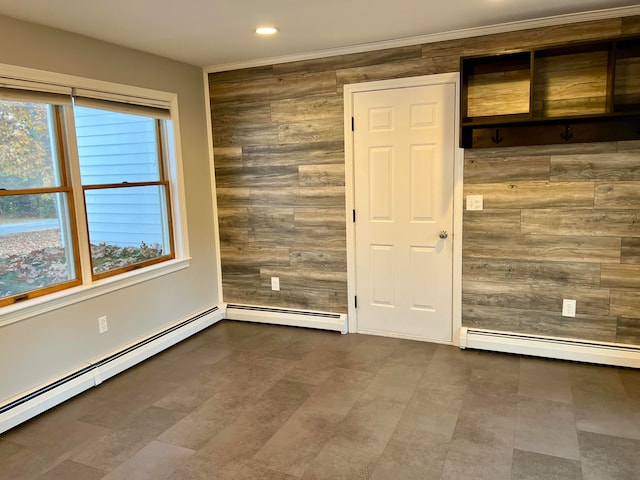 empty room featuring a baseboard heating unit and wooden walls