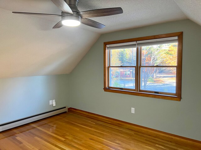 bonus room with light hardwood / wood-style flooring, vaulted ceiling, a baseboard radiator, a textured ceiling, and ceiling fan