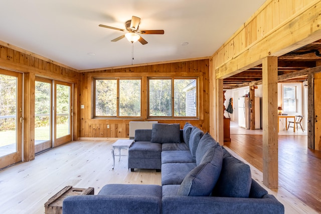 living room featuring lofted ceiling, light wood-type flooring, and wood walls