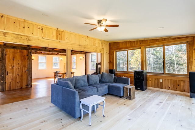 living room featuring light hardwood / wood-style floors, wood walls, a wealth of natural light, and ceiling fan