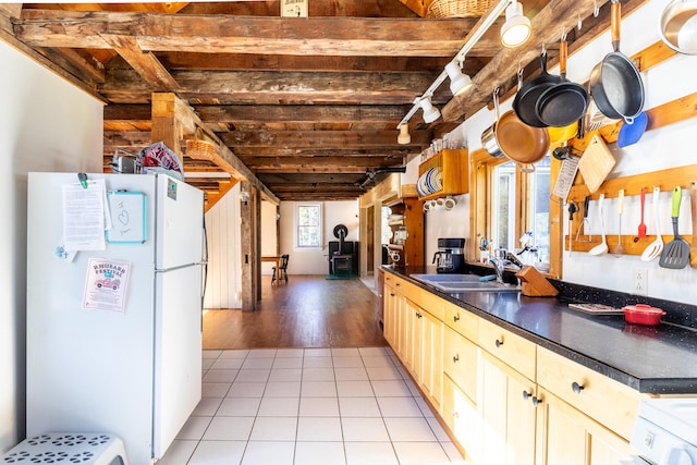 kitchen with beam ceiling, light brown cabinetry, light wood-type flooring, white fridge, and sink