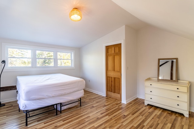 bedroom with vaulted ceiling, light hardwood / wood-style flooring, and multiple windows