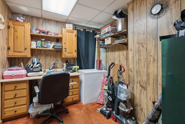 office area featuring wood walls, a paneled ceiling, and dark colored carpet