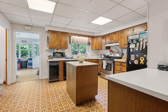 kitchen featuring a paneled ceiling, black appliances, plenty of natural light, and a kitchen island