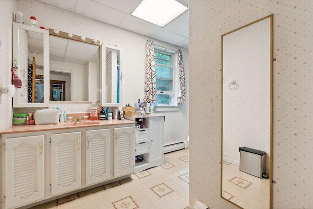 bathroom with vanity, a drop ceiling, and a baseboard heating unit