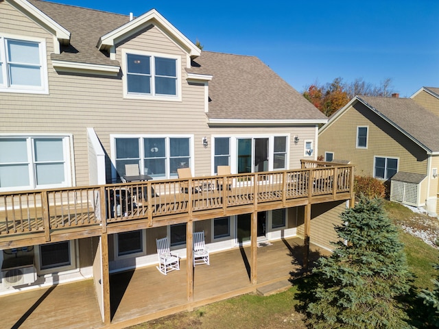 back of property featuring a wooden deck, a shingled roof, and a patio