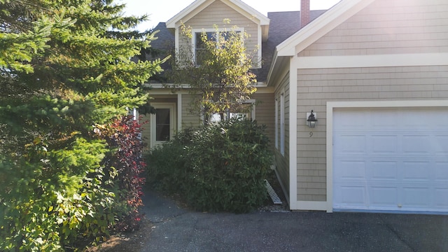 exterior space with roof with shingles and an attached garage