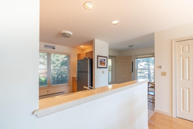 kitchen with freestanding refrigerator, a peninsula, recessed lighting, light wood-type flooring, and a baseboard radiator