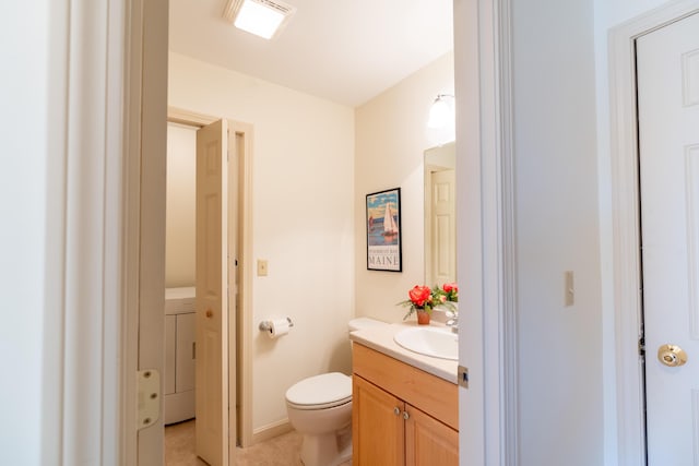 half bathroom with washer / clothes dryer, toilet, tile patterned floors, and vanity