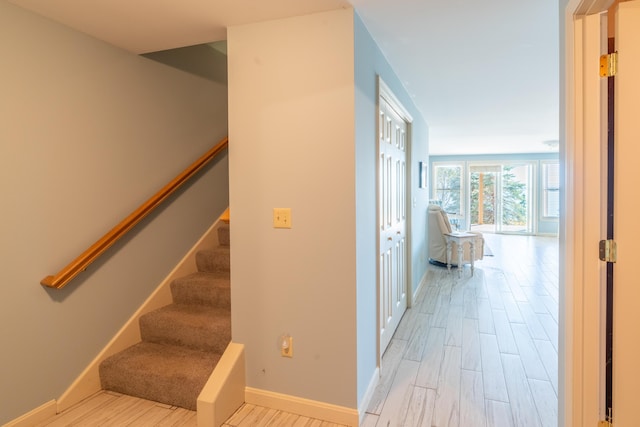 corridor featuring stairway, baseboards, and wood finished floors