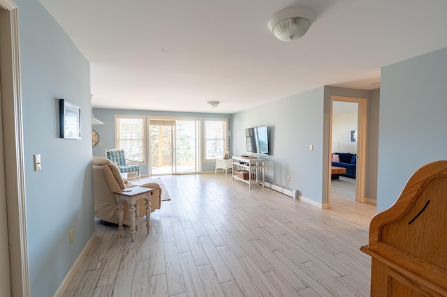 living area with light wood-style floors, baseboards, and a baseboard heating unit
