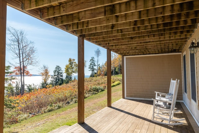 wooden deck with a lawn and a water view