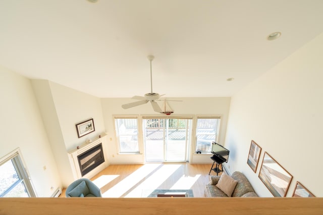 living room featuring a glass covered fireplace, light wood-style floors, ceiling fan, recessed lighting, and vaulted ceiling