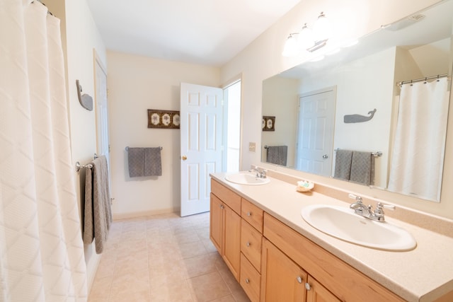 bathroom featuring baseboards, double vanity, tile patterned floors, and a sink