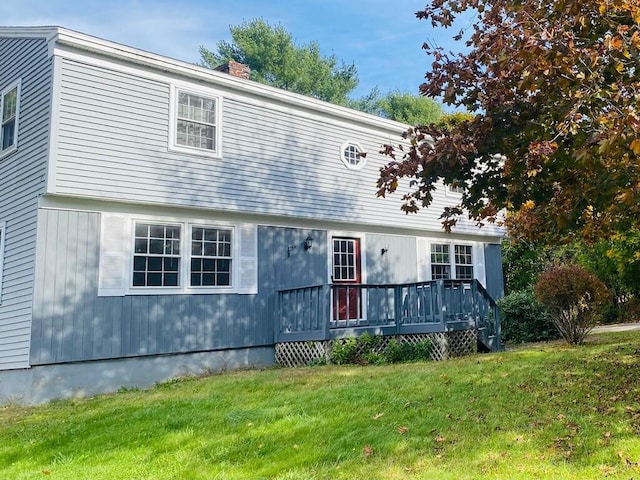 view of front facade with a wooden deck and a front lawn