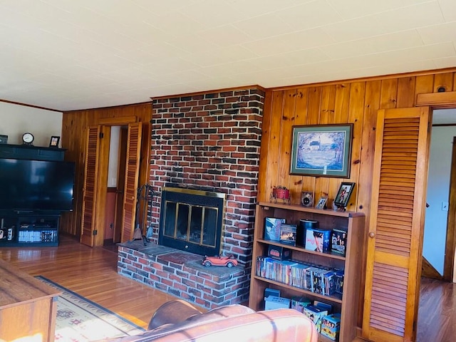 living room with wood walls, dark hardwood / wood-style floors, and a brick fireplace