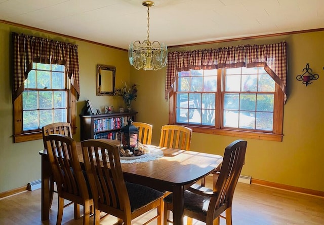 dining space with ornamental molding, hardwood / wood-style flooring, a chandelier, and a wealth of natural light