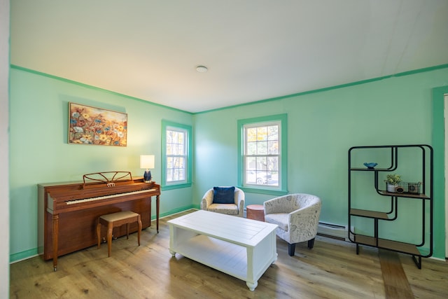 sitting room with crown molding, a baseboard radiator, and light wood-type flooring