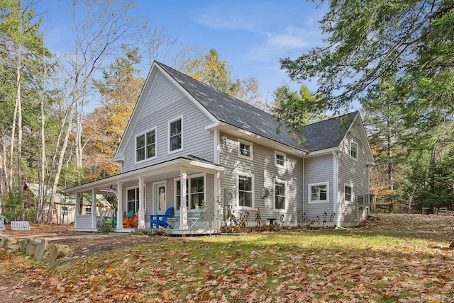 rear view of property featuring covered porch and a yard