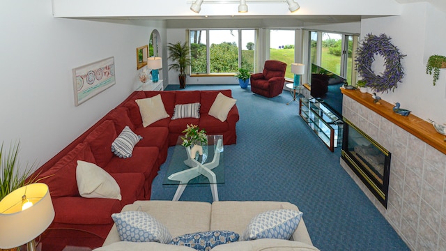 carpeted living room featuring a tiled fireplace and rail lighting