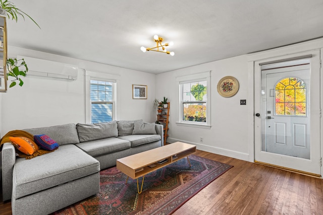 living room featuring a notable chandelier, hardwood / wood-style flooring, an AC wall unit, and a wealth of natural light