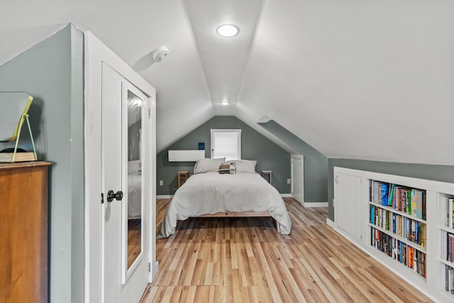 bedroom with vaulted ceiling and light hardwood / wood-style flooring