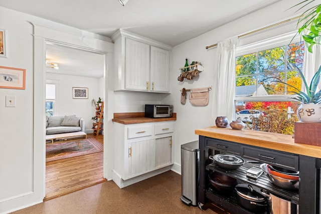 kitchen with dark wood-type flooring, white cabinetry, and wood counters