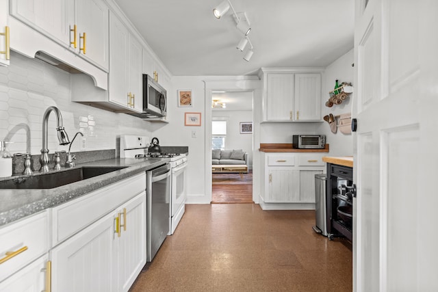 kitchen with appliances with stainless steel finishes, sink, white cabinetry, rail lighting, and dark wood-type flooring