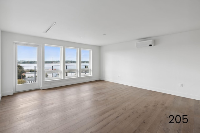 unfurnished room featuring a wall unit AC and light hardwood / wood-style floors