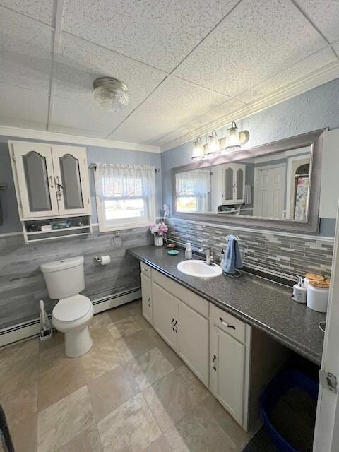 bathroom featuring a baseboard heating unit, decorative backsplash, vanity, and toilet