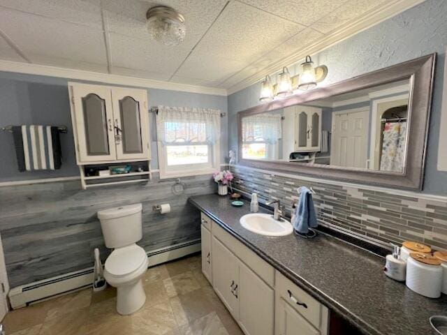 bathroom featuring a baseboard heating unit, vanity, toilet, and crown molding