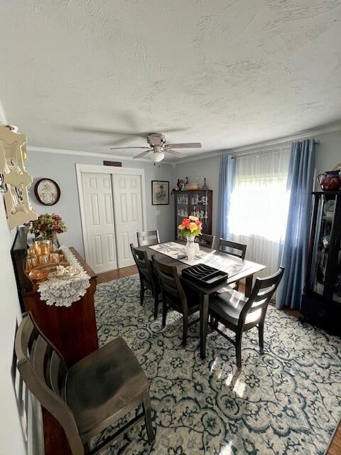 dining space with light wood-type flooring, a textured ceiling, crown molding, and ceiling fan