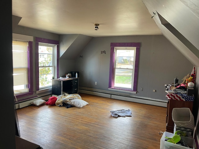 additional living space with a baseboard radiator, hardwood / wood-style flooring, and lofted ceiling